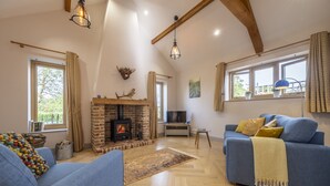 A spacious living room with a fireplace, blue sofas, and a television.
