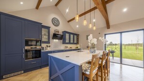 A modern kitchen with blue cabinets, a large island, and a dining area with wooden chairs.
