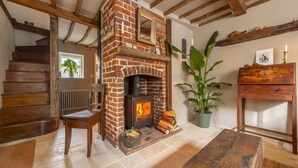 Una habitación acogedora con chimenea de ladrillo, escalera de madera y una planta en maceta.