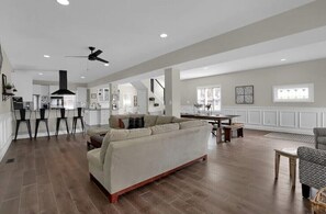 Relax in this spacious living area with a sofa and dining table, featuring a high ceiling and ceiling fan for a well-ventilated atmosphere.