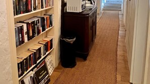 A hallway with bookshelves, a trash bin, a desk with a lamp, and a door labeled "Sauerland". - Hotel Pemü (Arnsberg)