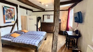 A rustic room with a bed, a desk, a chair, and a TV. - Hotel Pemü (Arnsberg)