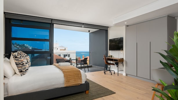 Een moderne slaapkamer met een groot bed, een bureau en uitzicht op de oceaan.