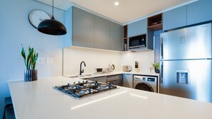 A modern kitchen with a central island, stainless steel appliances, and a pendant light. - Stunning Sea Views , Inverter , Steam Room (Umhlanga)