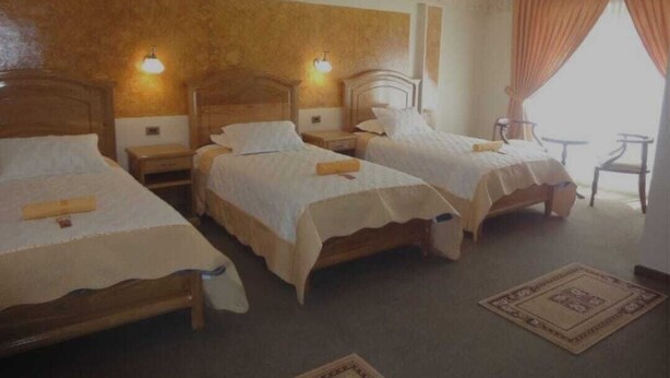 Habitación de hotel con dos camas individuales, una mesita y una silla.