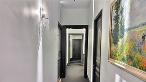 Ein Flur mit einem Kronleuchter, Türen und einem Gemälde an der Wand.