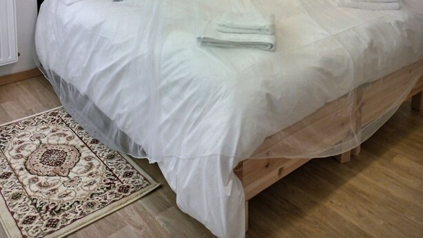 Ein Schlafzimmer mit einem Himmelsbett, einem gemusterten Teppich und einer Wand mit runden Verzierungen.