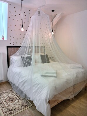 Quarto com cama sob um dossel, tapete estampado e parede com decorações circulares.