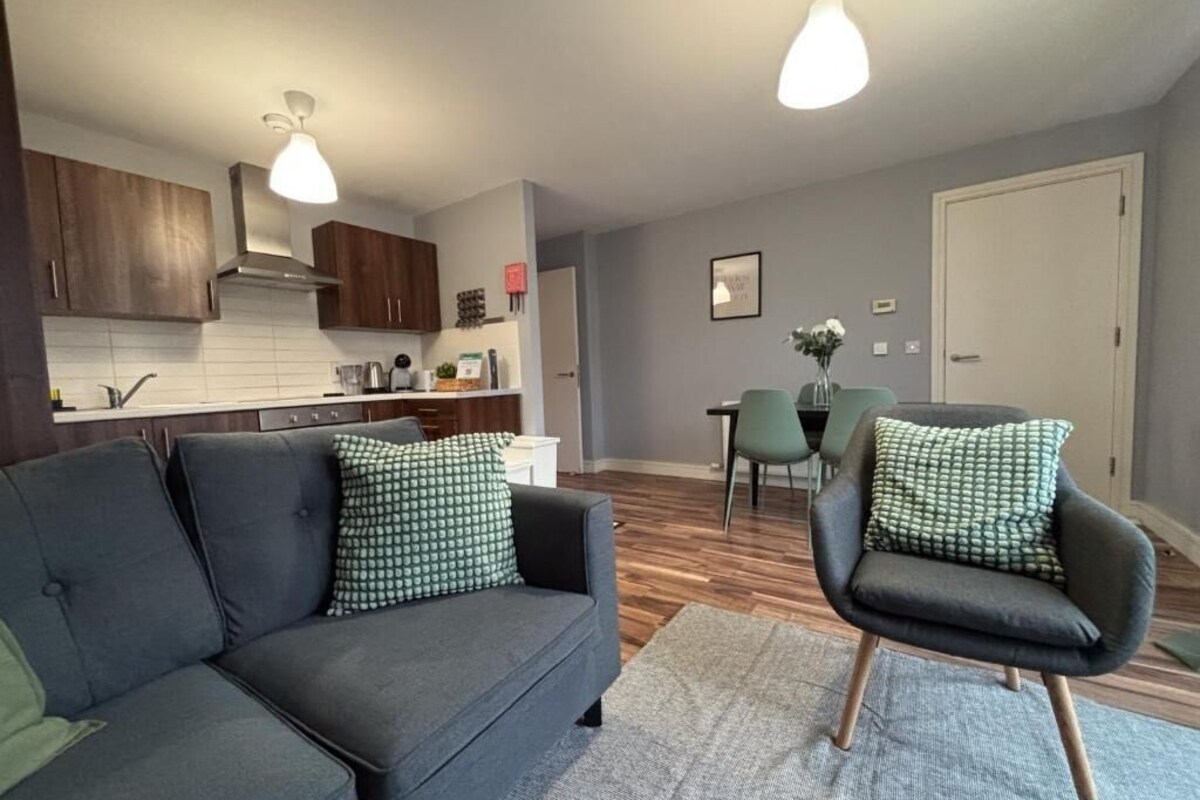 A modern living room with a sofa, armchair, and dining area with chairs and a table.