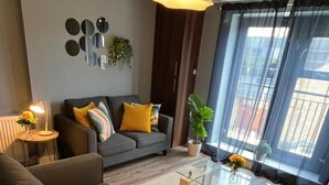 Una sala de estar moderna con un sofá, una mesa de centro y un amplio ventanal con cortinas.