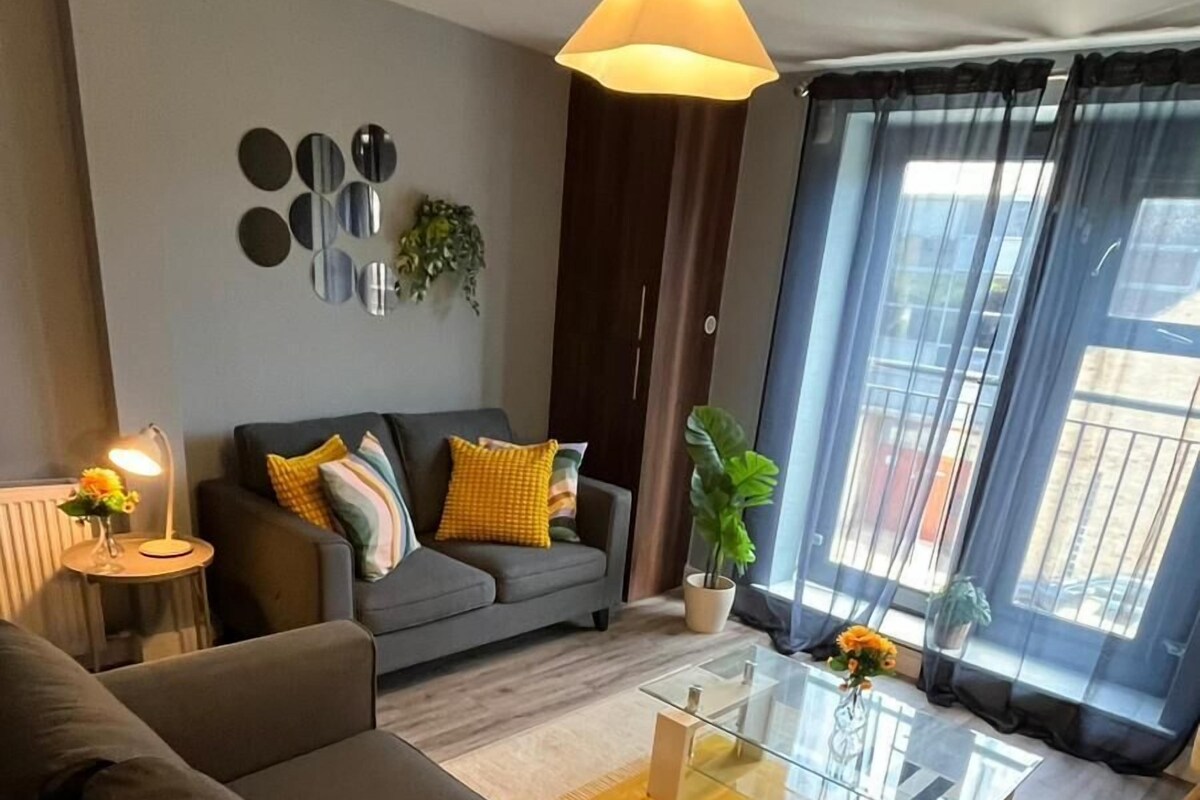 A modern living room with a sofa, coffee table, and a large window with curtains.