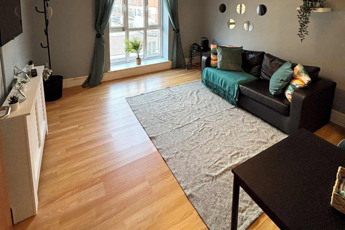 A modern living room with a sofa, a coffee table, a dining table, a TV, and a window with curtains.