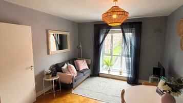 Ein Zimmer mit einer Couch, einem Esstisch, einer Hängelampe und einem Fenster mit Blick.
