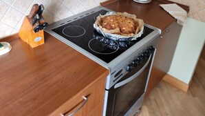 A kitchen with a stove, oven, and wooden cabinets. - Home-spirit apartment with a panoramic window in the heart of Klaipėda! (Klaipeda)