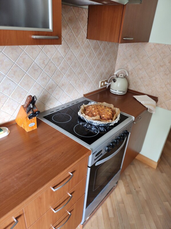 A kitchen with a stove, oven, and wooden cabinets.