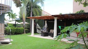 Ein überdachter Außenbereich mit einer Pergola, einer Hängematte und einem kleinen Tisch.