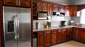 A kitchen with wooden cabinets, a stainless steel refrigerator, a microwave, and a coffee maker. - 12B Jaco Sol Quadplex - Luxury apartment near the beach and commerce (Jacó)