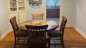 Un comedor con una mesa y sillas de madera, un armario y un letrero decorativo de bienvenida.