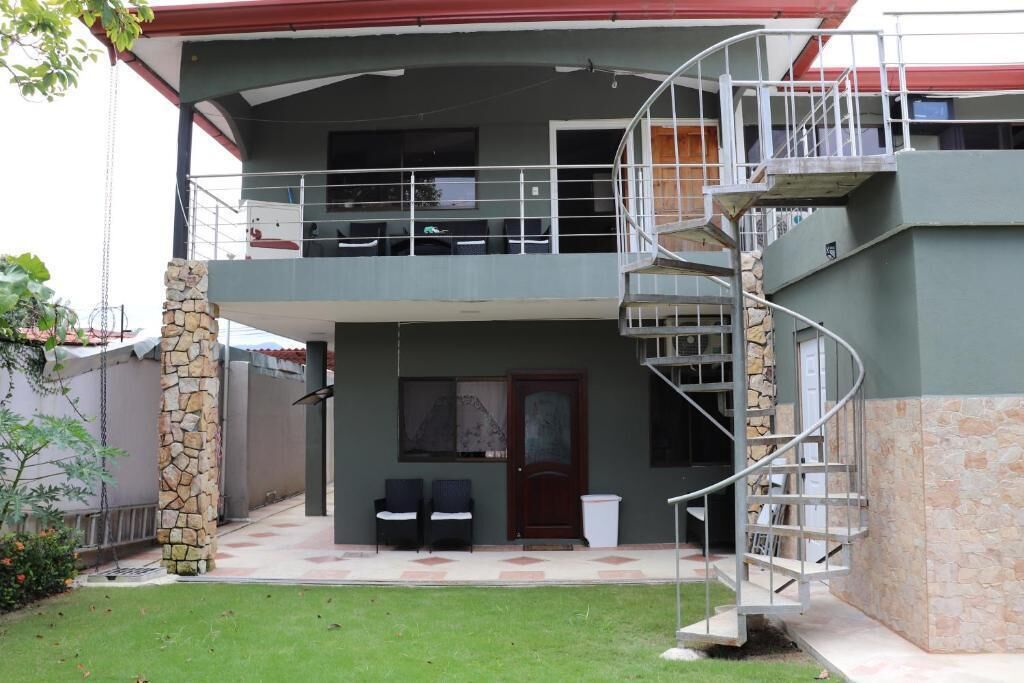 Un bâtiment à deux étages doté d’un escalier en colimaçon, d’un pilier en pierre et d’un petit espace extérieur aménagé avec des chaises.