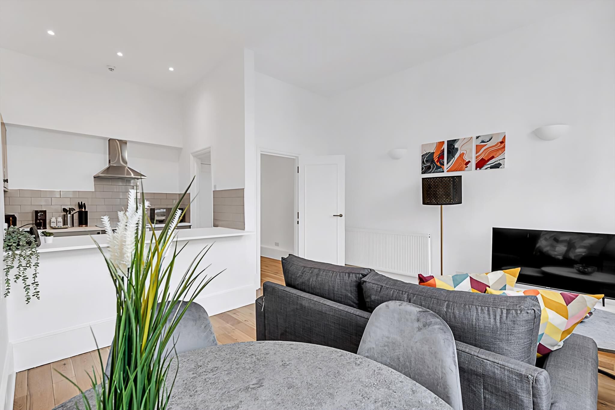 A modern living room with a grey sofa, a flat-screen TV, and abstract wall art.