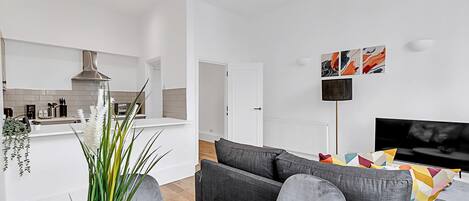A modern living room with a grey sofa, a flat-screen TV, and abstract wall art.