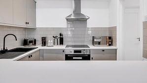 Een moderne keuken met een roestvrijstalen afzuigkap, een inbouwoven, een broodrooster en een magnetron.