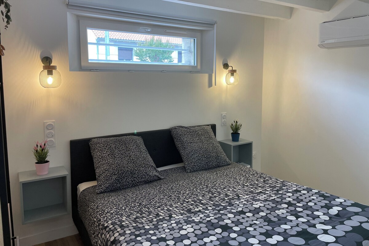 Une chambre à coucher comprenant un lit, deux tables de chevet, une fenêtre et des lampes fixées au mur.