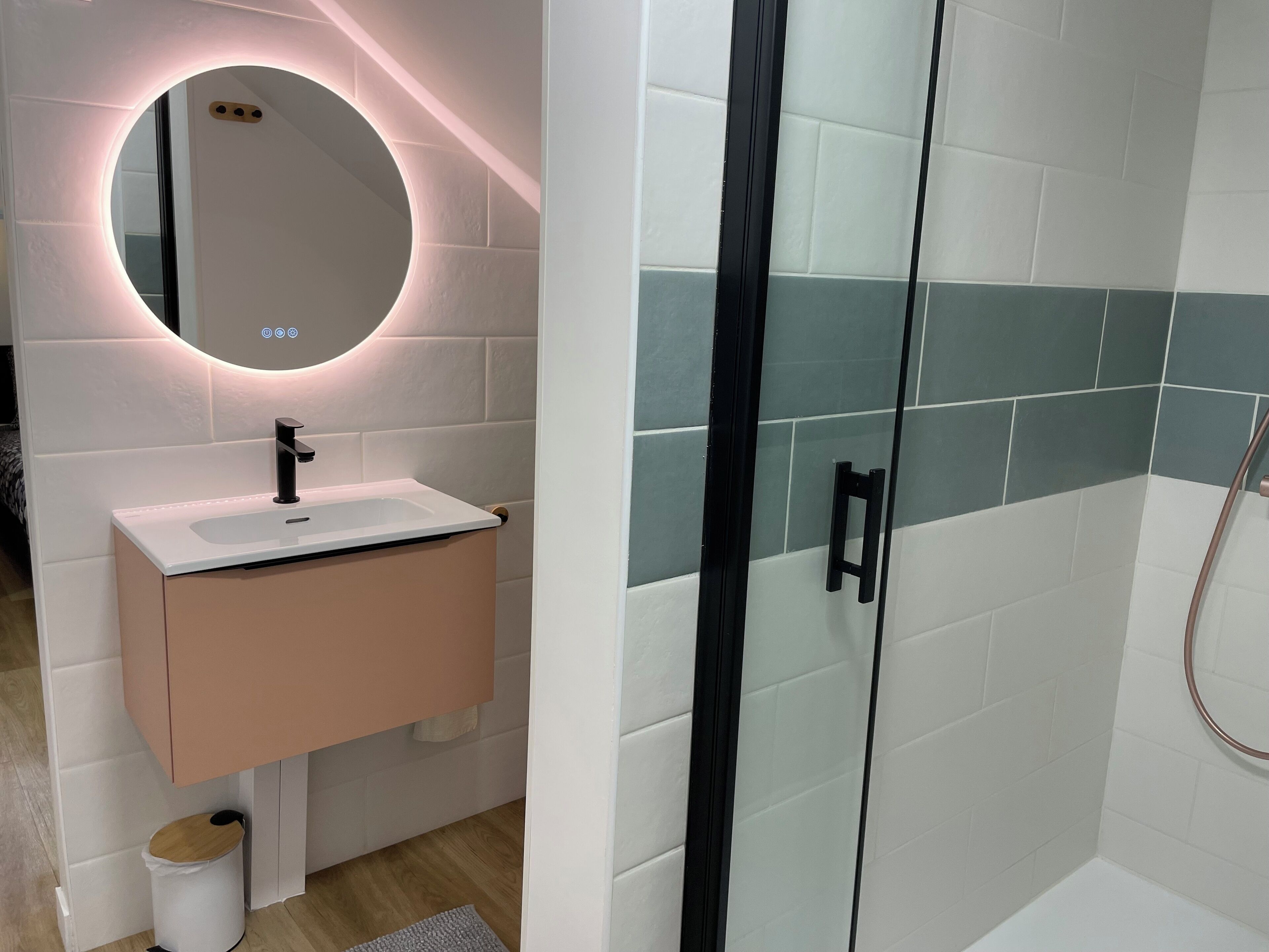 A modern bathroom with a round mirror, a sink, and a shower area.