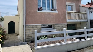 A two-story building with a balcony, a window with a flower box, and a white fence.