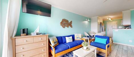 Una sala de estar con un sofá, una mesa de centro, un televisor y un adorno de pez montado en la pared.