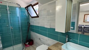 Une salle de bain moderne avec une douche à parois de verre, des toilettes blanches, un lavabo et un meuble-lavabo en bois.