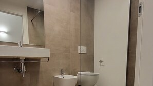 A modern bathroom with a glass shower enclosure, a sink, and a toilet. - Bertiera Rooms (Bologna)