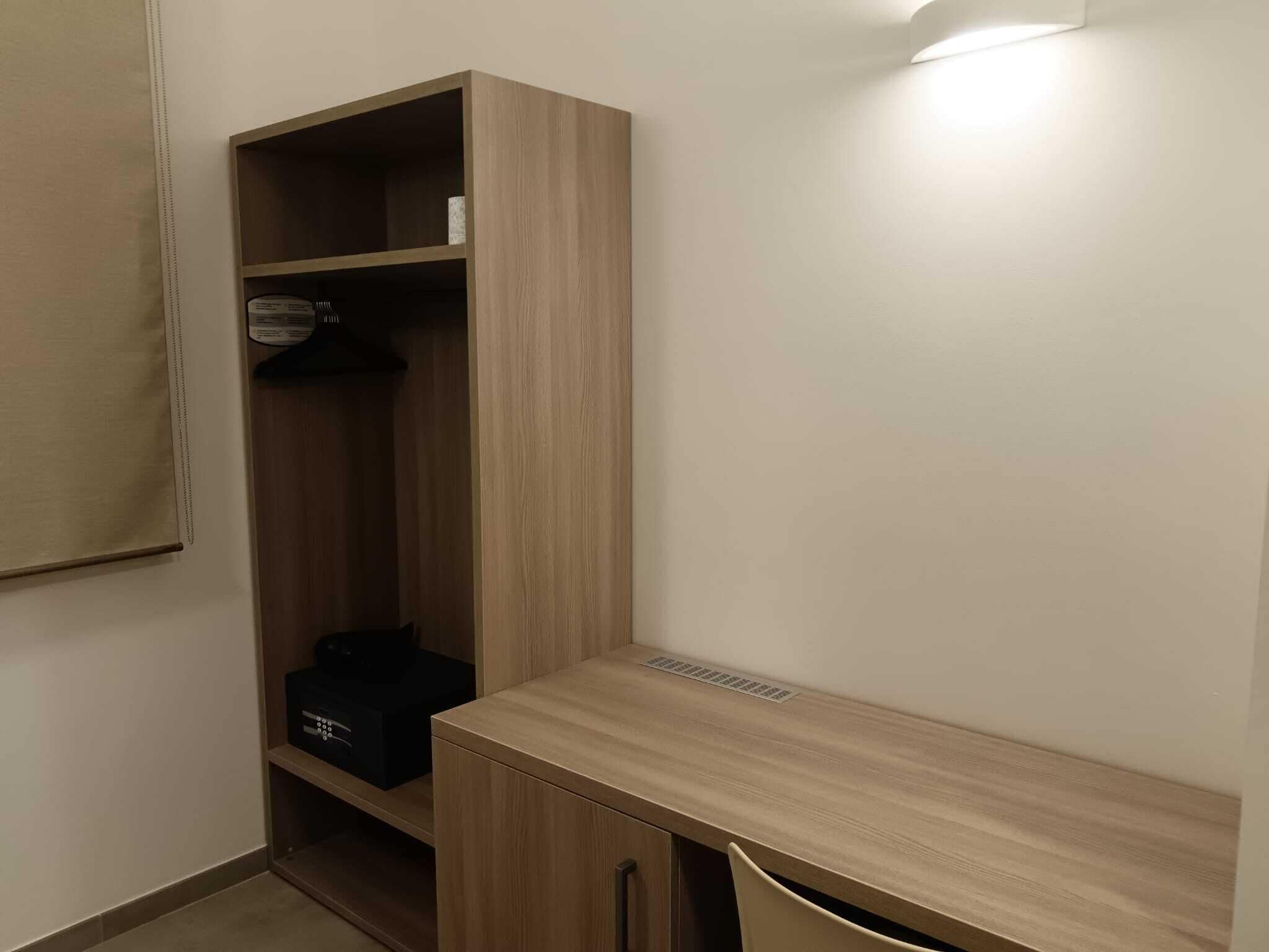 A small room with a wooden desk and a built-in wardrobe.