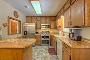 Una cocina con armarios de madera, electrodomésticos de acero inoxidable y encimera de madera.