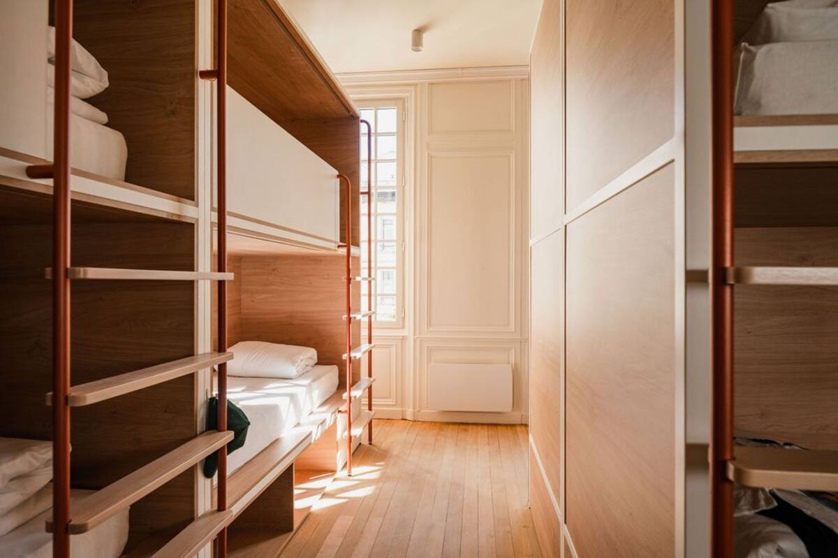 A narrow hallway with wooden bunk beds and a radiator on the wall.