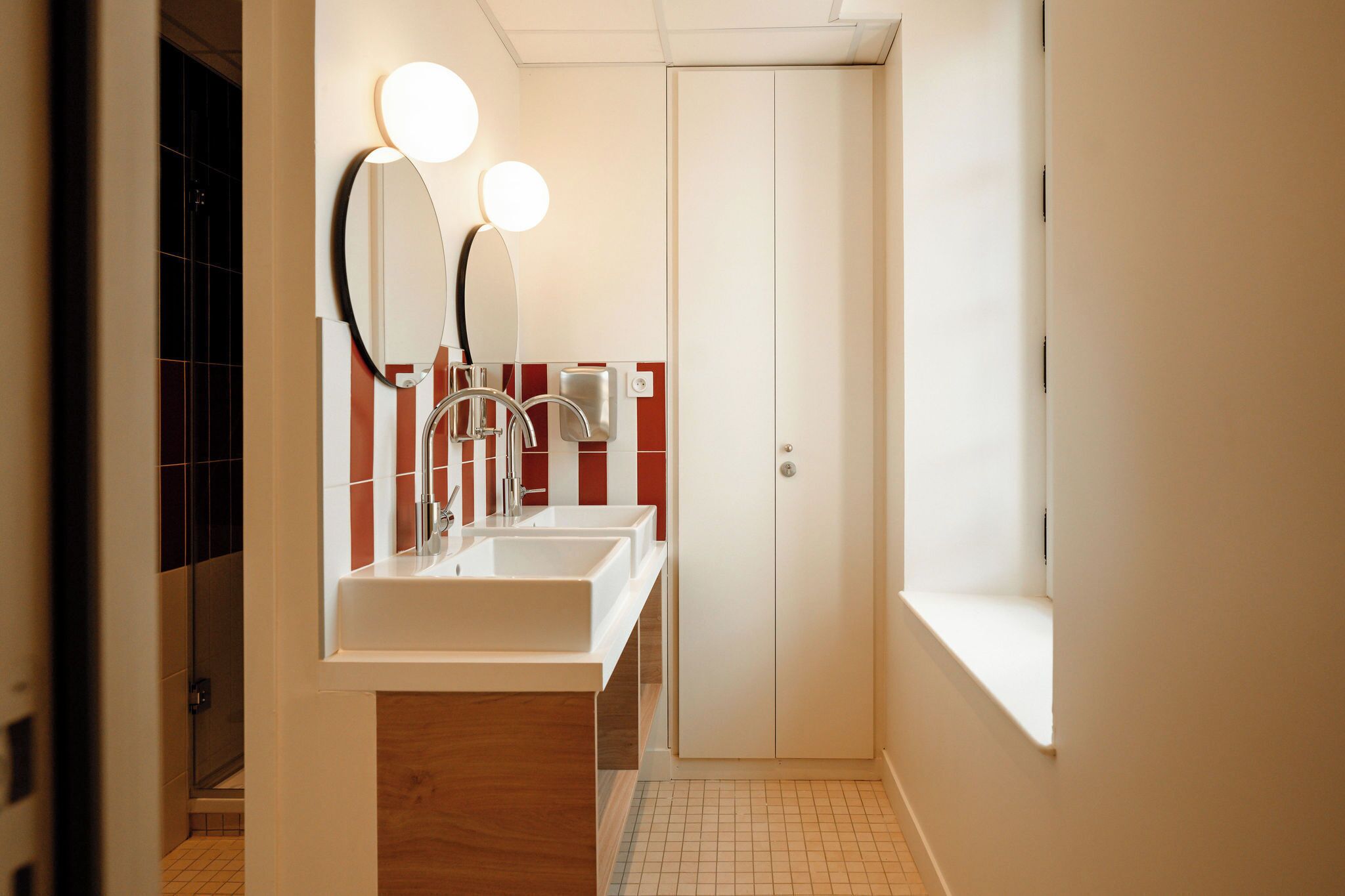Ein modernes Badezimmer mit zwei Waschbecken, einem Spiegel und einem Fenster.