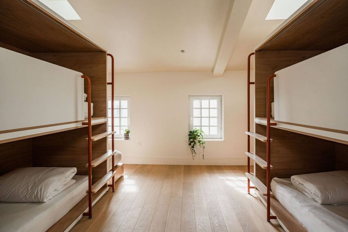 A dormitory room with bunk beds, wooden floors, and a skylight.