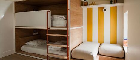 A compact room with a bunk bed, a small seating area, and a window with a view.