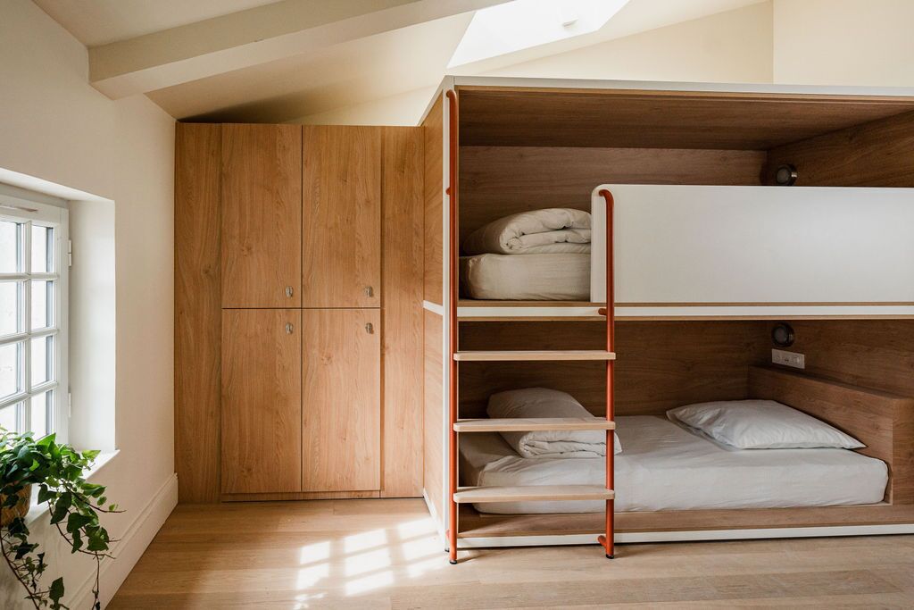 A loft bedroom with a wooden wardrobe, a bunk bed, and a skylight.