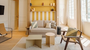 A living room with a sofa, a chair, a small table, and a shelf with decorative items. - CENTRAL (La Rochelle)