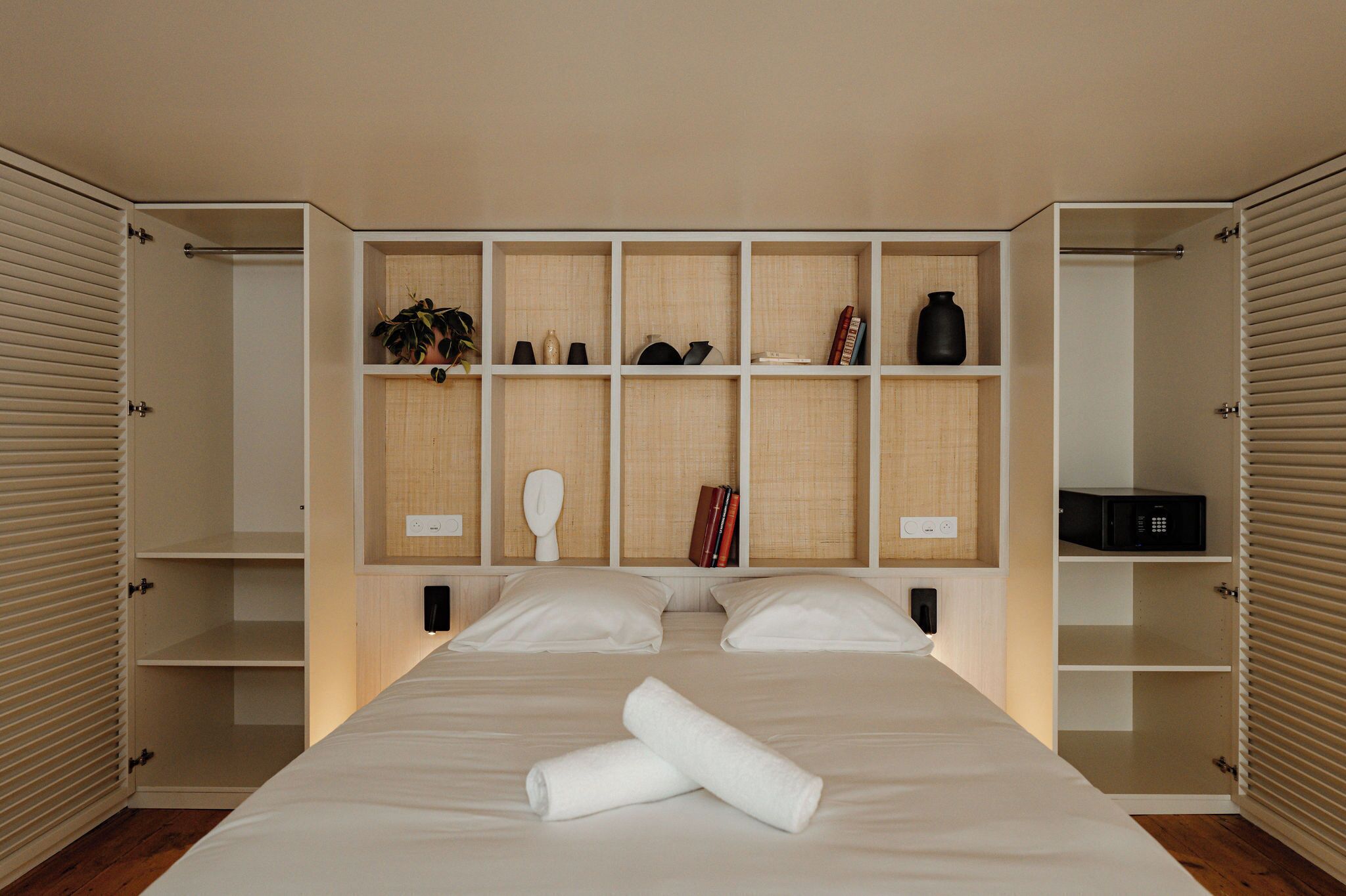A bedroom with a large bed, built-in shelving, and a bedside table.