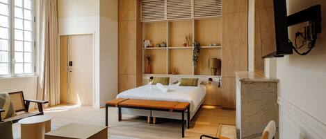 Una habitación de hotel moderna con una cama grande, un escritorio y una zona de estar.