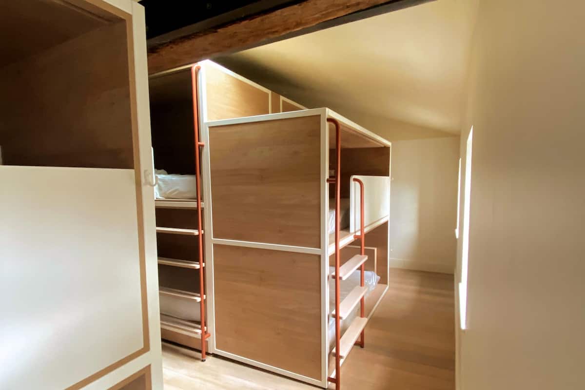 An attic bedroom with wooden floors, a sloped ceiling, and a built-in wardrobe.