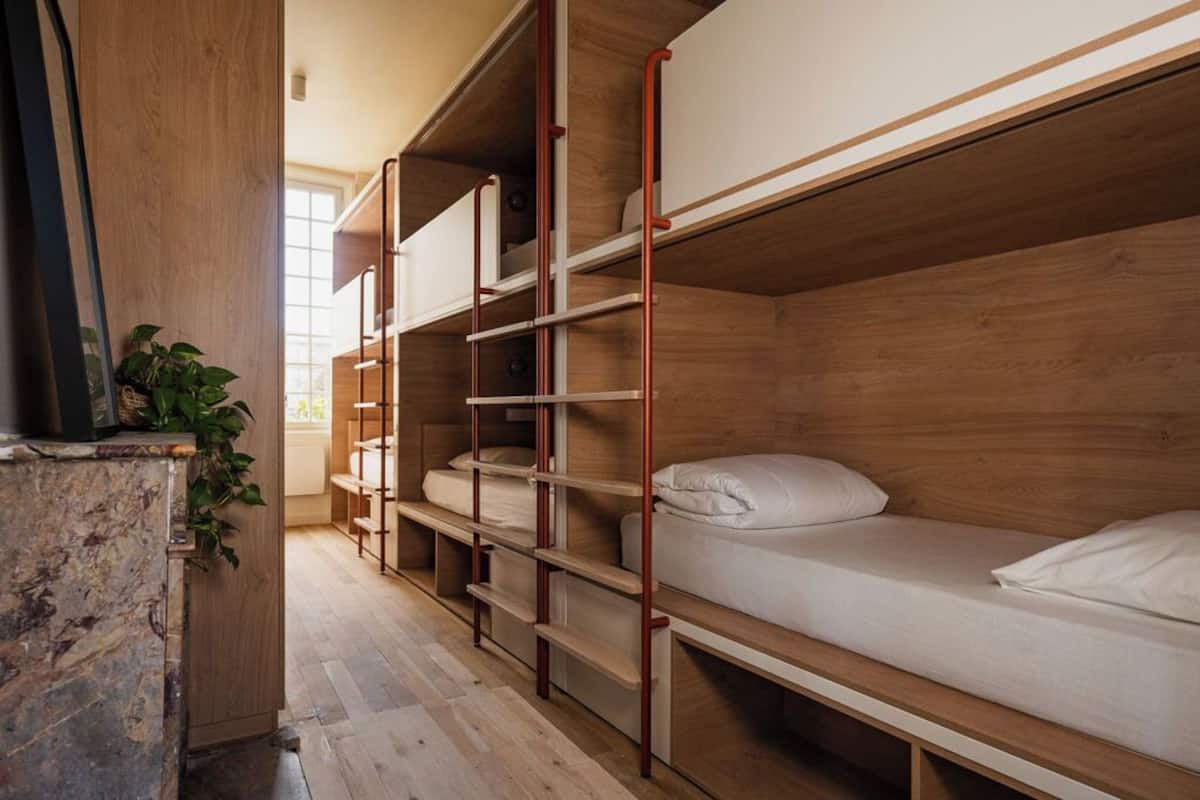 A bunk bed room with wooden walls and metal railings, a marble counter, and a potted plant.