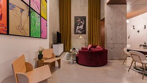 A modern living room with a wooden sofa, a red velvet chair, and a dining area with a white table and chairs. - Majestic Heights: Retreat in La Condesa (Ciudad de México)