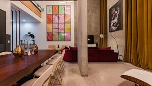 A modern dining area with a wooden table, white chairs, and a red sofa. - Majestic Heights: Retreat in La Condesa (Ciudad de México)