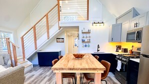 A modern kitchen with a wooden dining table, built-in appliances, and a staircase leading to an upper level. - Brand New, Private Home w/ Nordic Hot Tub- Just 1/2 mile to Jay Peak Resort (Jay)