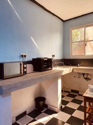 Kitchen area with a toaster and coffee maker, sink, and window above.