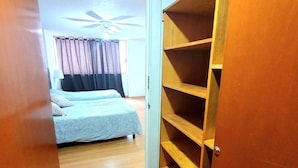 Une chambre à coucher avec un lit, un ventilateur de plafond et une armoire en bois.
