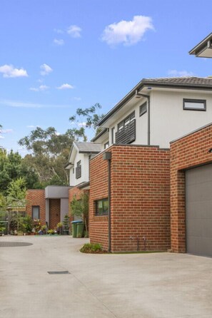 A modern residential area with brick houses, a concrete driveway, and a clear blue sky. - StayAU Modern 4BRM TH Bayswater (Bayswater North)